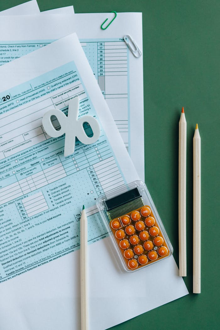 services-img-01 Flat lay of tax documents, calculator, and pencils on green surface.