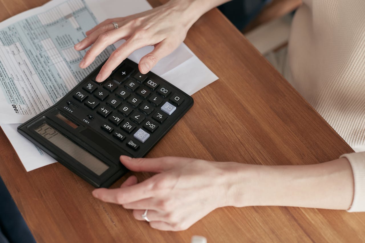 services-04 Close-up of a woman using a calculator and reviewing bills at home.